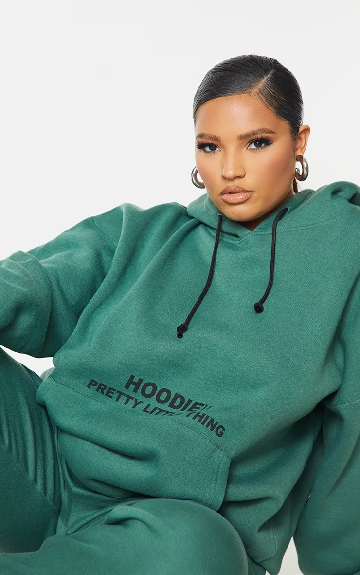 PRETTYLITTLETHING Plus Hoodie vert oversize à poche devant et slogan imprimé